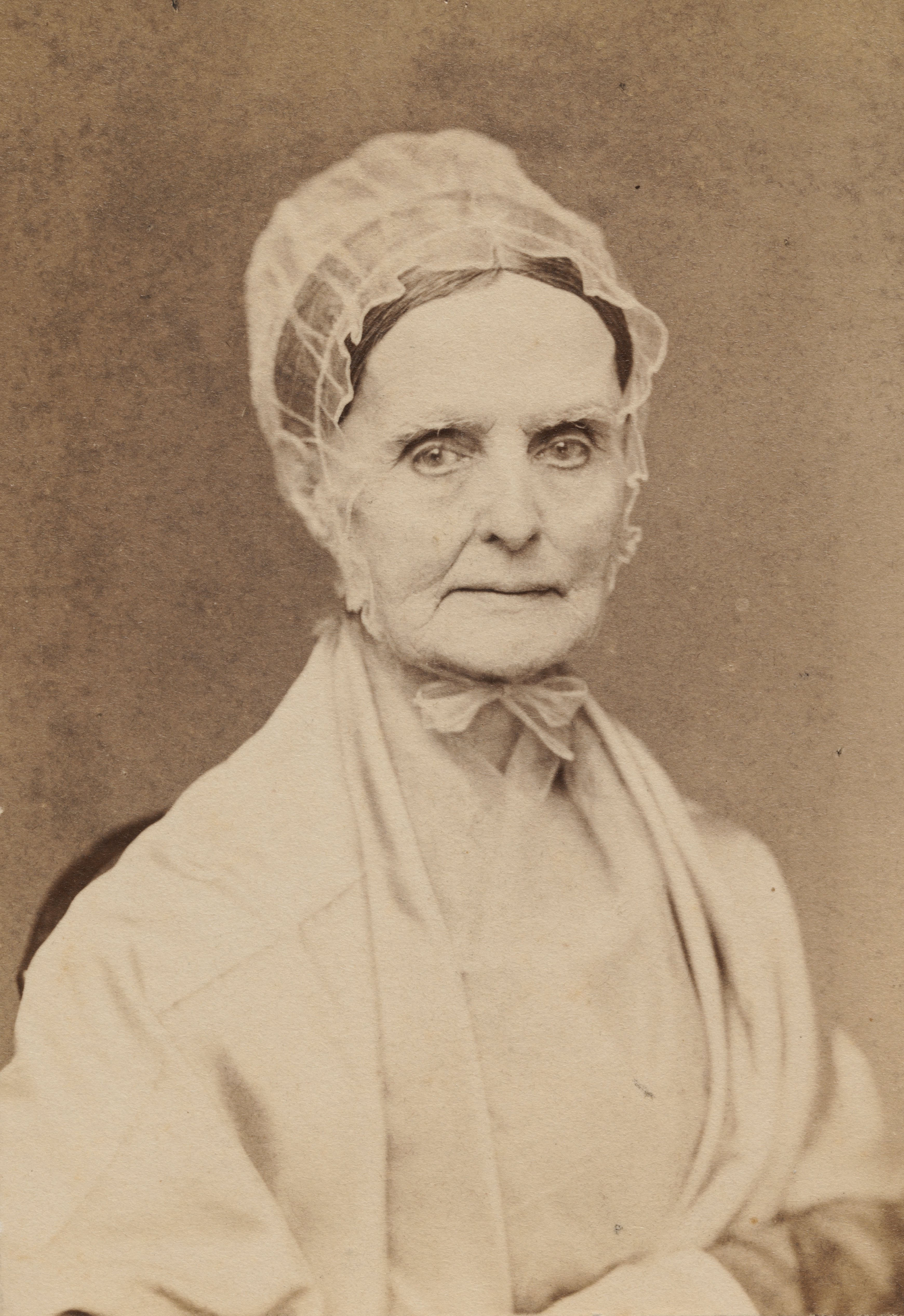 portrait photograph of an elderly woman wearing a bonnet, white sweater, and bow at the neck, facing the camera.